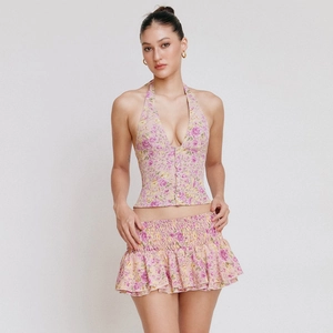 Detail view of pink floral two-piece set featuring halter V-neck top and ruffle mini skirt