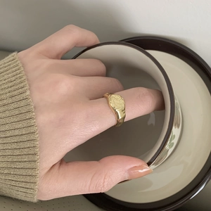 Detailed view of irregular textured gold ring styled with a minimalist knit sweater