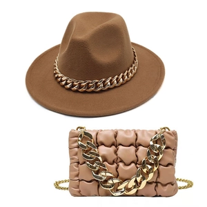 Brown wide-brim fedora hat and pink pleated shoulder bag with chunky gold chains