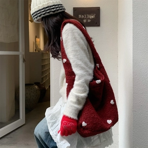 Detail of red plush tote bag with white heart embroidery styled for winter street fashion
