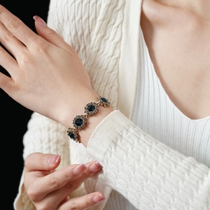 Gros plan d'un bracelet vintage avec pierres bleu foncé et montures florales dorées