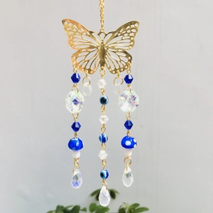 Macro shot of metal butterfly charm with blue evil eye beads and crystal pendants