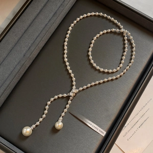 Elegant Y-shaped pearl necklace with zircon accents and silver tassel on velvet display