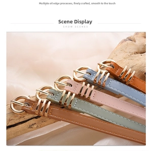 Detail view of five thin faux leather belts with golden round buckles and three-ring keepers