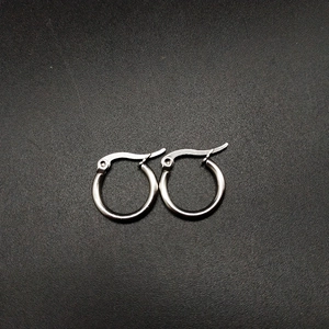 Macro shot of silver stainless steel hoop earrings with engraved texture on black surface