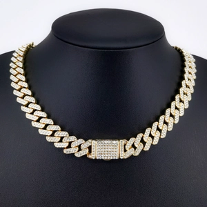 Detailed view of a gold-colored iced out Cuban link chain necklace on a black mannequin