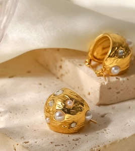 Détail macro de boucles d'oreilles en perles dorées 18K avec texture lave et cristaux