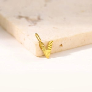 Golden Letter V Pendant with radiant texture on minimalist white marble background