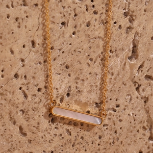Détail macro du pendentif barre plaqué or 18 carats avec nacre sur fond de pierre