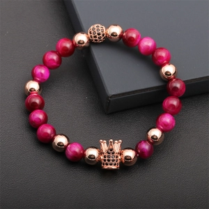 Macro shot of crown charm bracelet with rose red tiger eye stones and rose gold beads
