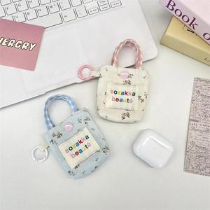 Detailed macro view of floral fabric earphone pouch with letter patch and metal hook