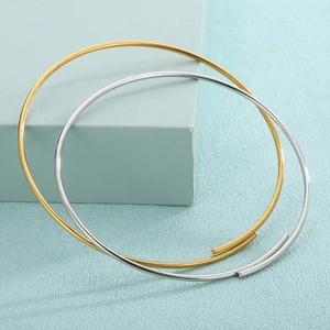 Minimalist open gold and silver stainless steel bangles for women on a blue geometric prop
