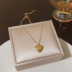 Macro detail of gold heart pendant with Love engraving on a velvet jewelry box