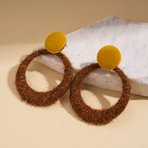 Detail of brown flocked hoop earrings with golden glitter and yellow stud on marble