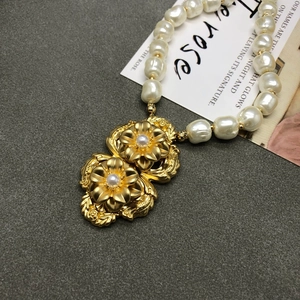 Detailed macro of gold plated floral pendant with pearls on a vintage style necklace