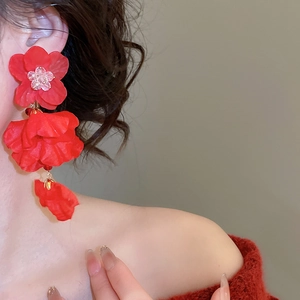 Macro shot of large red fabric flower earrings with rhinestone center on model