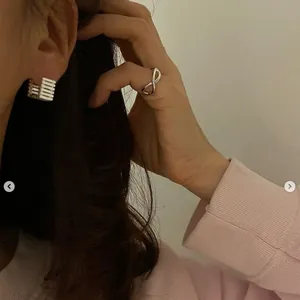 Close-up of minimalist S925 silver square hoop earring with stripe pattern and infinity ring