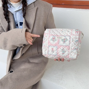 Trousse de maquillage matelassée à fleurs rose et blanc tenue par un mannequin