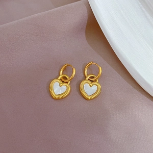 Detail of heart-shaped shell earrings with golden frames on silk fabric