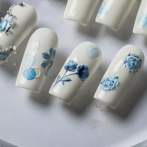 Blue 3D floral embossed nail stickers with pearls on white polished base nails