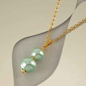 Detailed close-up of a gold gourd pendant with green pearls on a fine chain