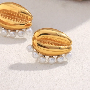 Close-up of 18K gold-plated shell earrings with embedded white pearls on beige surface