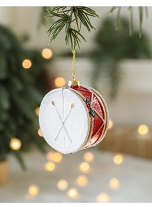 Close-up of red and white Christmas drum ornament with glitter hanging on pine branch