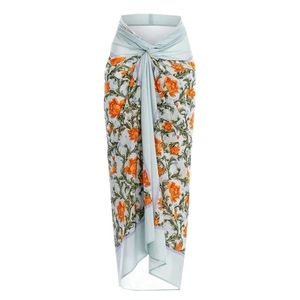Paréo en mousseline bleu clair avec fleurs oranges et détail noué sur le côté