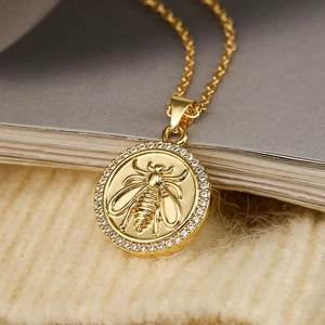 Elegante goudvergulde ronde ketting met bijenreliëf en zirkoonstenen op gebreide achtergrond
