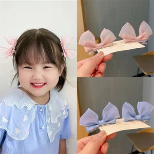Pink and blue butterfly hair clips with pearl tassels shown on child model and close-up