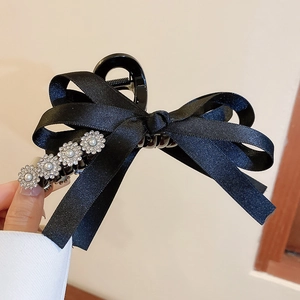 Détail d'une pince à cheveux à nœud en satin noir avec perles et fleurs en strass