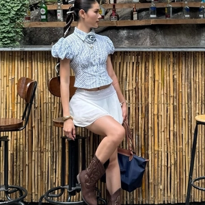 Women's blue striped short sleeve shirt with white lace mini skirt and brown cowboy boots