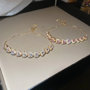 Close-up of adjustable gold chain bracelets with pink and white heart-shaped gemstones