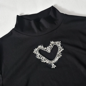 Detail of black ribbed knit top featuring a sparkling rhinestone heart design on chest