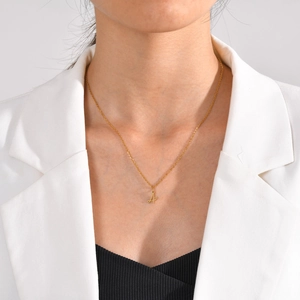 Close-up of a gold cursive letter A pendant on a stainless steel chain worn by a model
