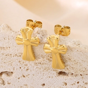 Macro detail of gold cross stud earrings featuring a polished mirror finish on stone
