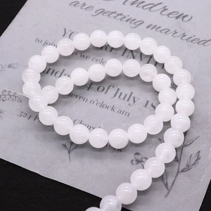 Polished white jade round beads for DIY jewelry making on vintage paper background