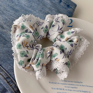 Detailed texture of a floral lace scrunchie with Sweety Girl tag on a white plate