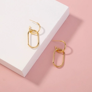 Detail of geometric gold chain link earrings with polished finish on a pink background