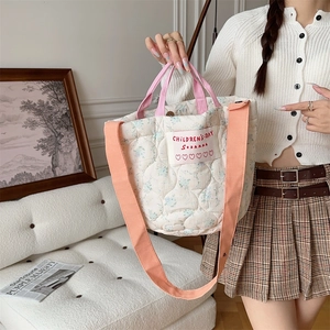 Détail d'un sac cabas fleuri matelassé avec poignées roses et bandoulière orange
