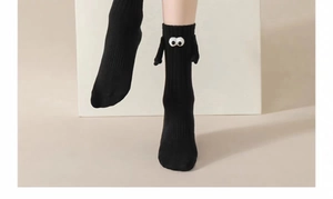 Close-up of black cotton socks with funny 3D eyes and magnetic hands in minimalist style