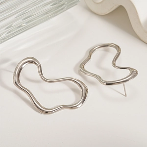 Macro shot of silver irregular wave stud earrings with polished metallic mirror finish