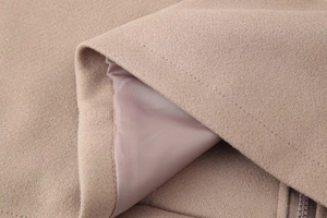 Detailed close-up of camel wool fabric and smooth silk lining on a cropped jacket