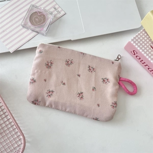 Rosa Stofftasche mit Blumenmuster, Reißverschluss und Trageschlaufe auf dem Schreibtisch