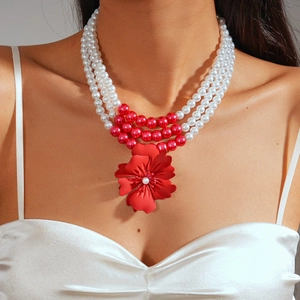 Detail of three-layer faux pearl necklace featuring red flower pendant and accent beads
