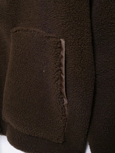 Detail of deep brown sherpa fleece texture with durable pocket stitching on casual jacket