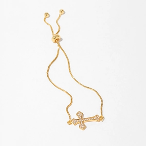 Detail of adjustable gold bracelet featuring a cross charm and shimmering white zircons