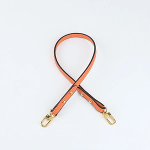 Detail of orange lychee leather bag strap with gold metal buckle and white stitching