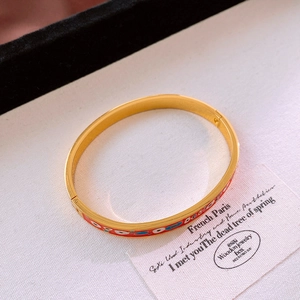 Gros plan sur un bracelet doré avec émail rouge et motif œil protecteur vintage