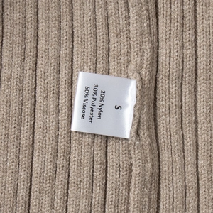 Detail of satin laundry label showing fabric composition on knitted rib dress